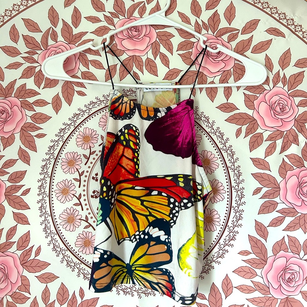 A cropped, spaghetti strap, racer back style top, white and a butter fly print.